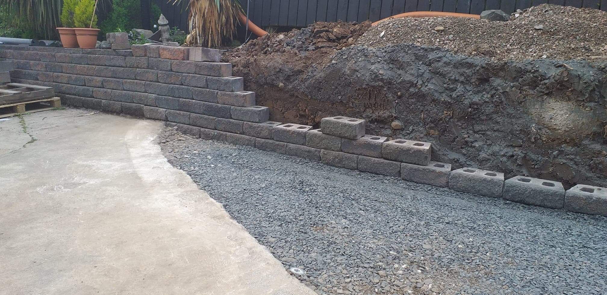 A finished block retaining wall edging a newly prepared driveway.