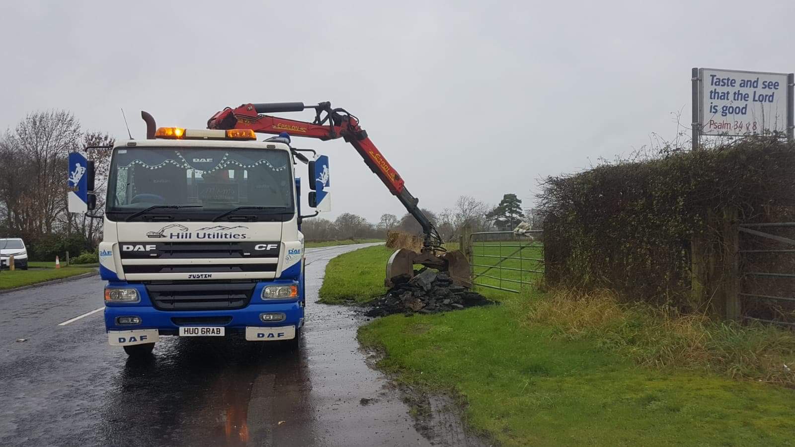 A Hill Utilities grab lorry loading material at the roadside.