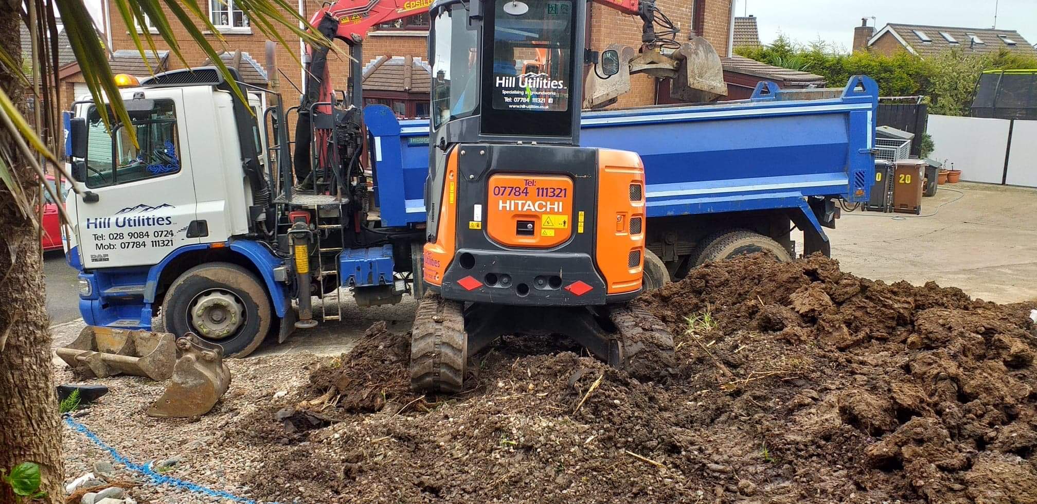 Excavator and dumper working together on a domestic garden groundworks project.