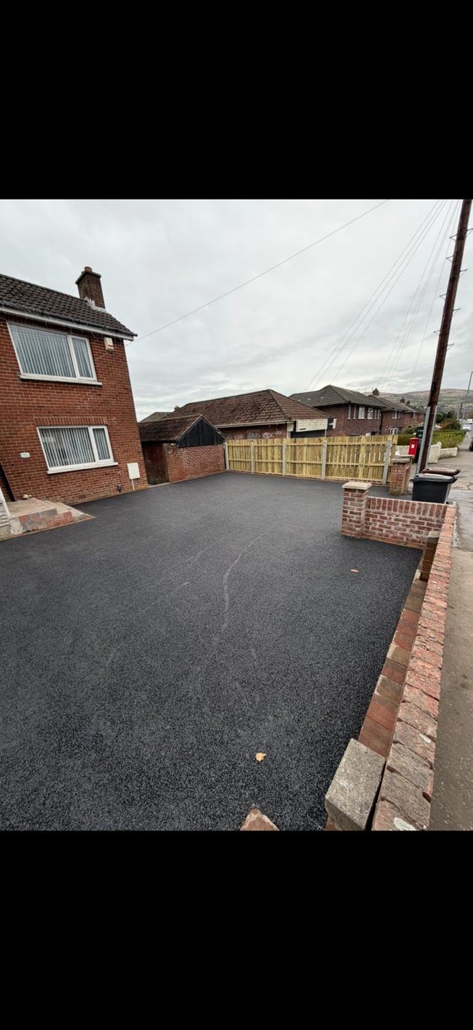 A completed tarmac driveway with a brick pillar and paviour edging.