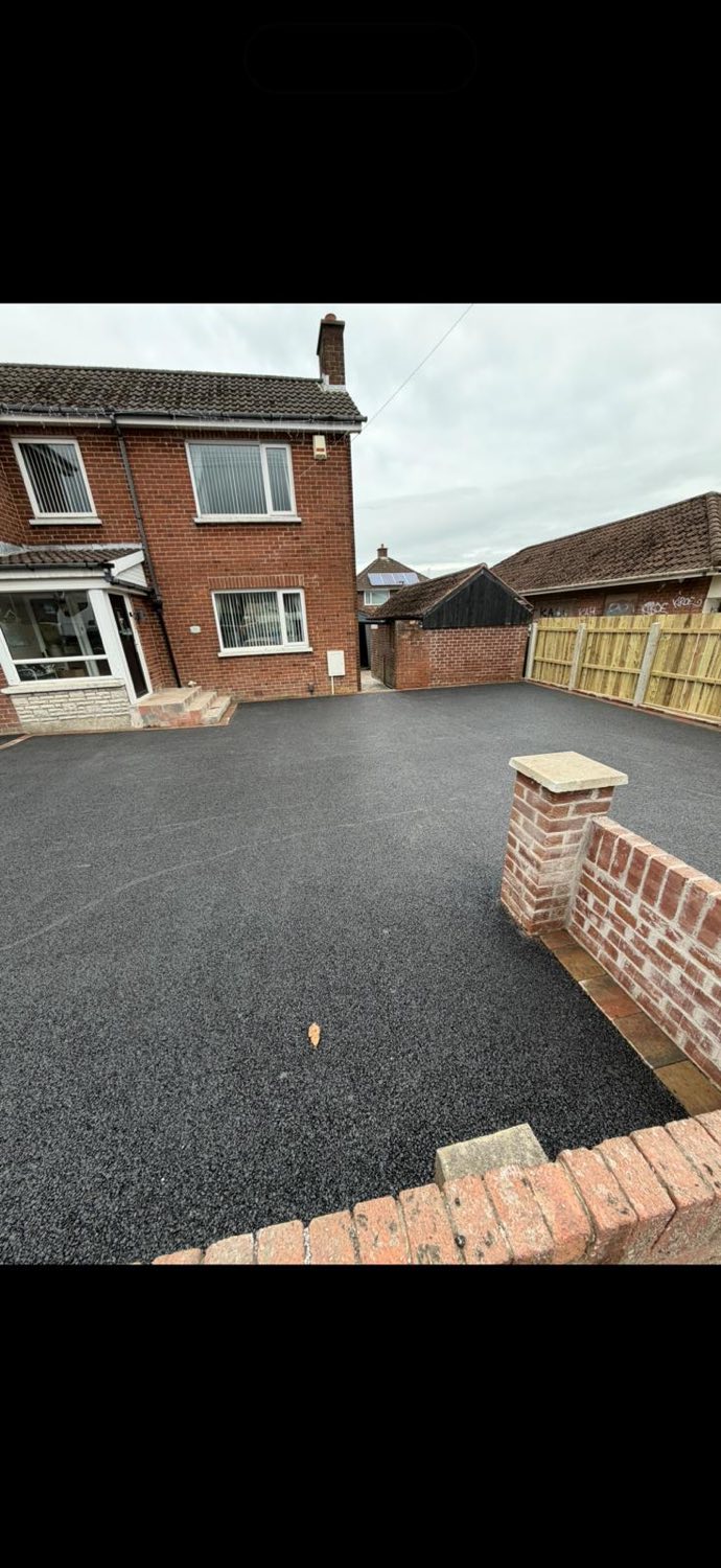 A newly laid tarmac driveway finished with brick edging and a feature pillar.