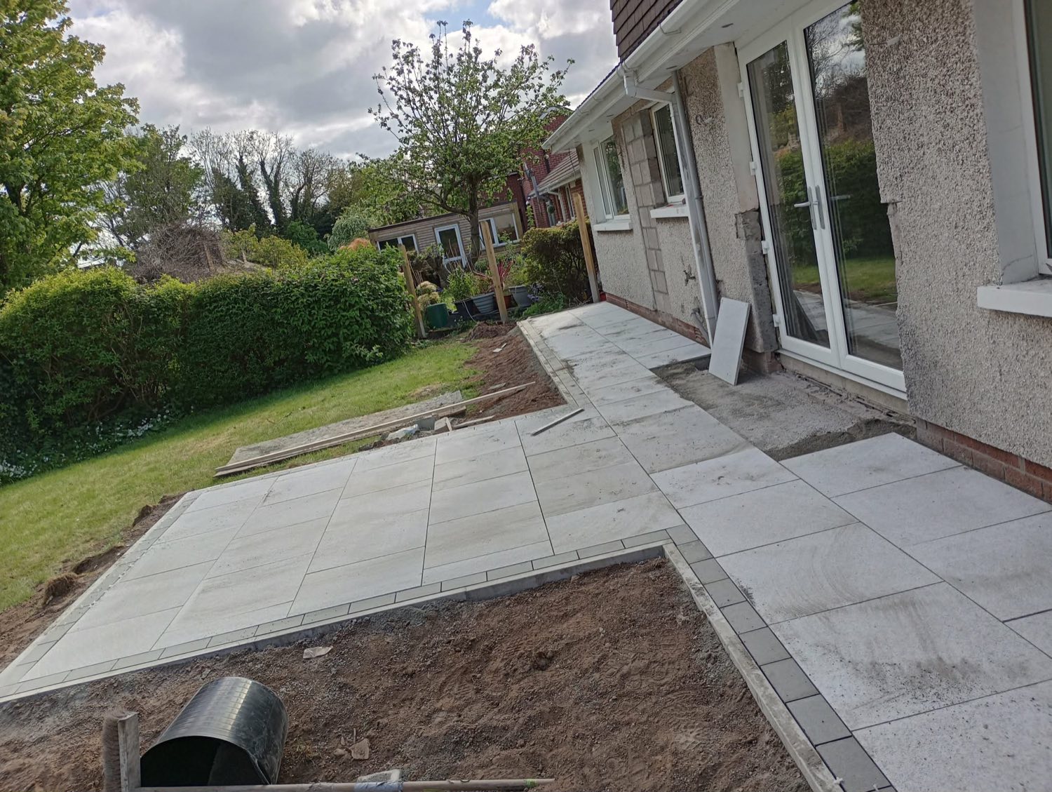 A new light-grey porcelain patio laid beside the house.