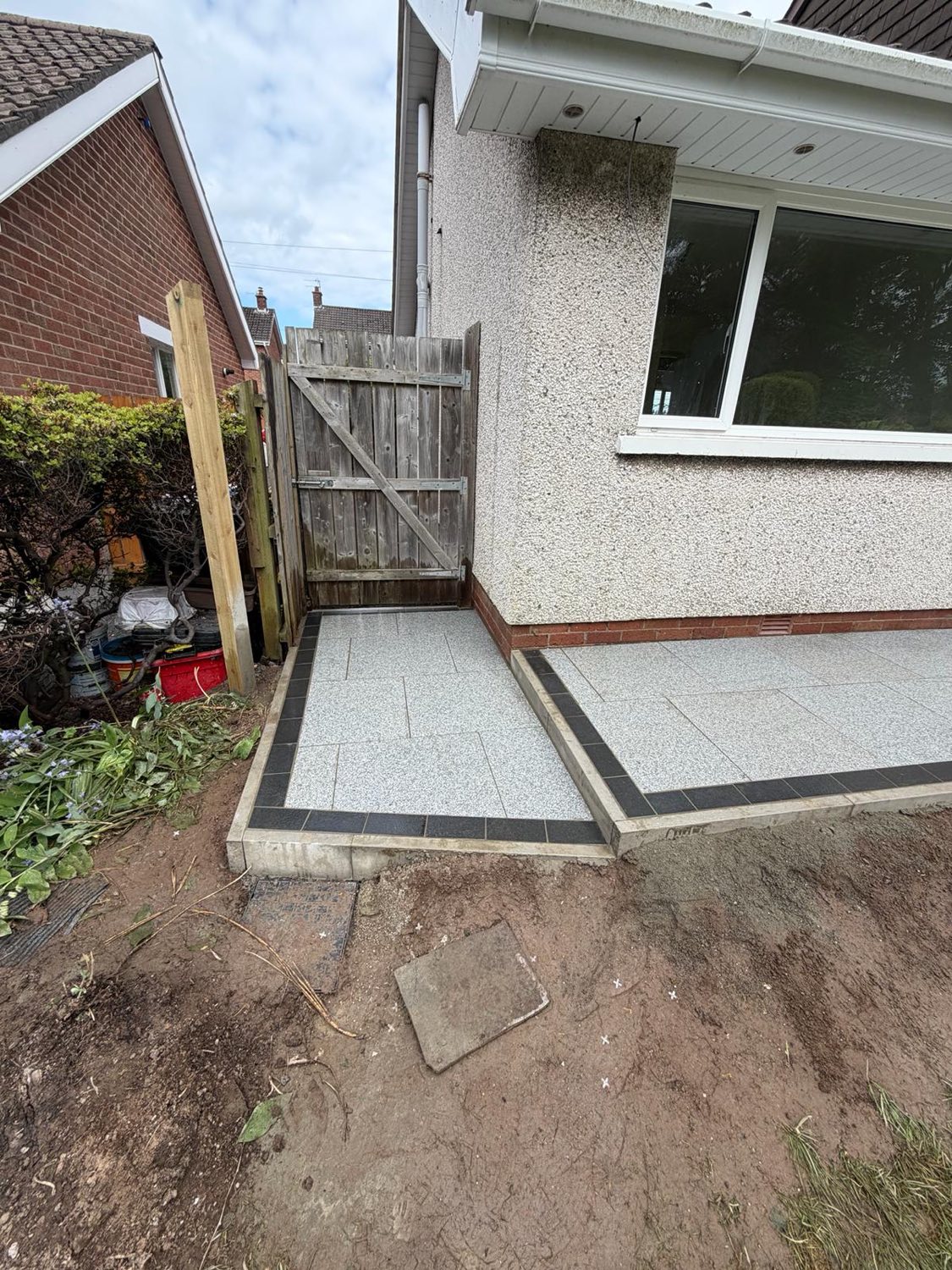 A porcelain patio with a charcoal border and step, finished to the side of a house.