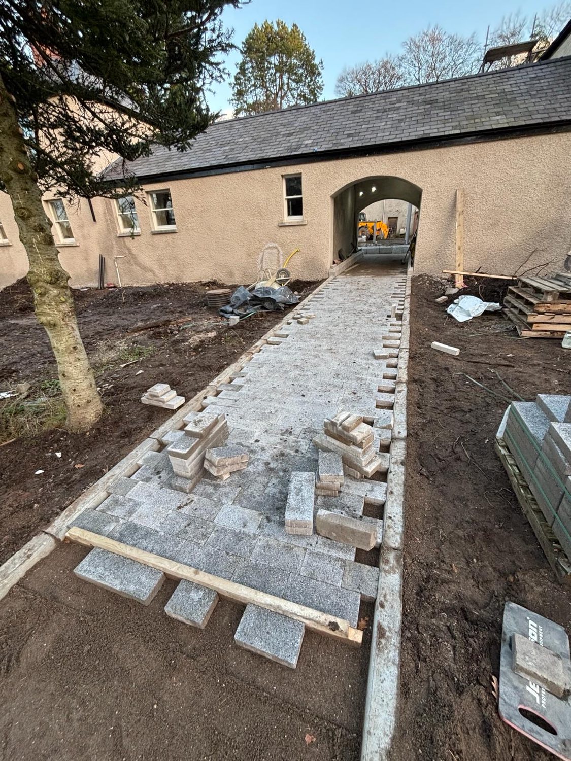 A new granite sett path being laid through a courtyard archway.