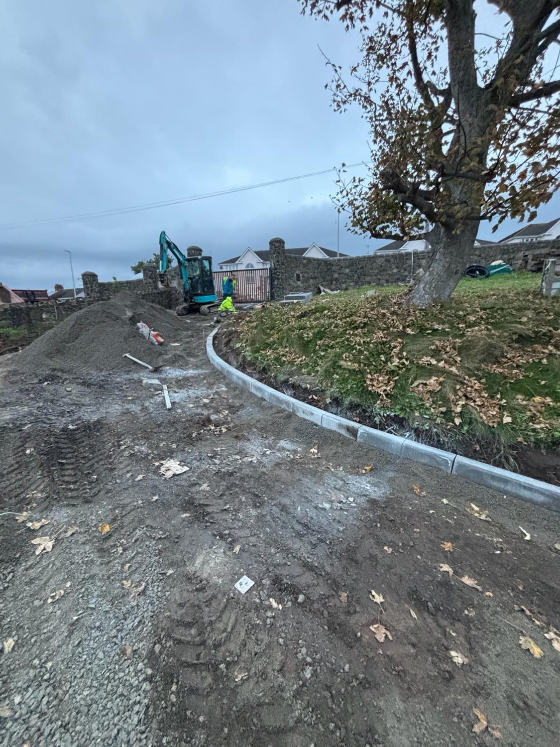 A curved concrete kerb being laid along a new driveway.