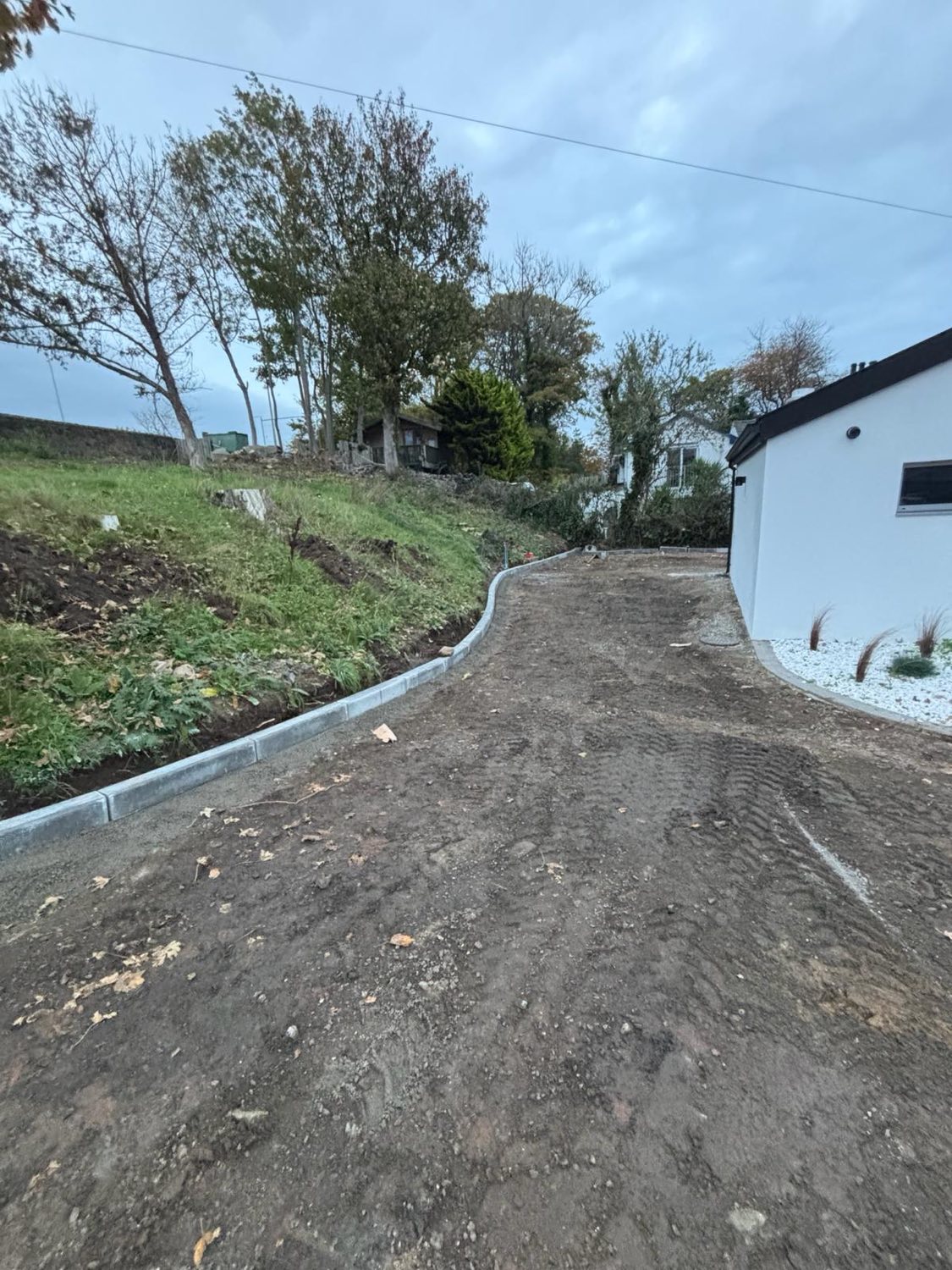 A freshly kerbed and graded driveway taking shape at a rendered house.