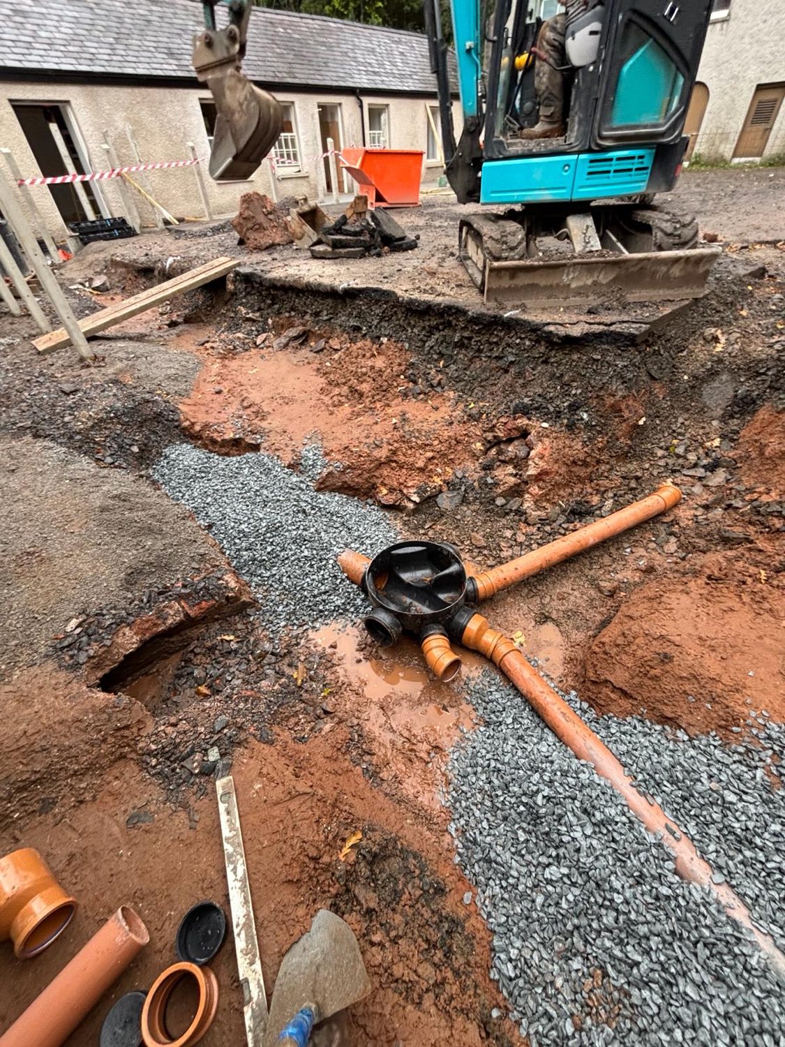Excavating to install new drainage and an inspection chamber in a courtyard.