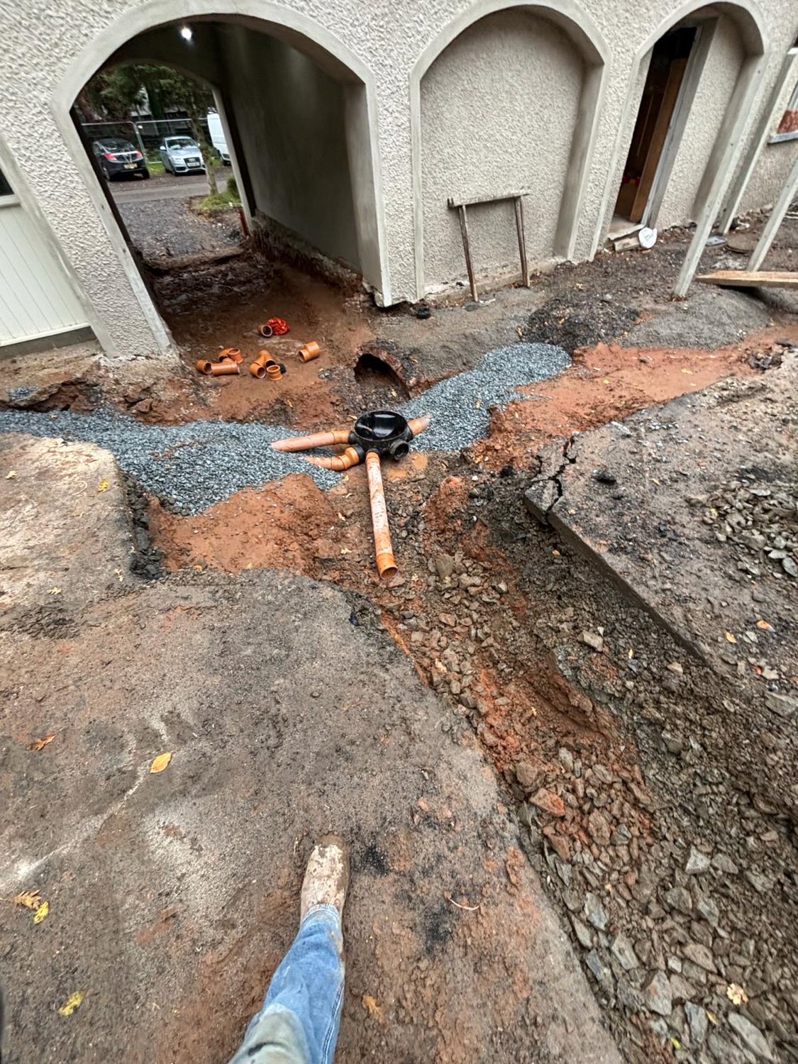 A new drainage run backfilled with gravel beneath an archway entrance.