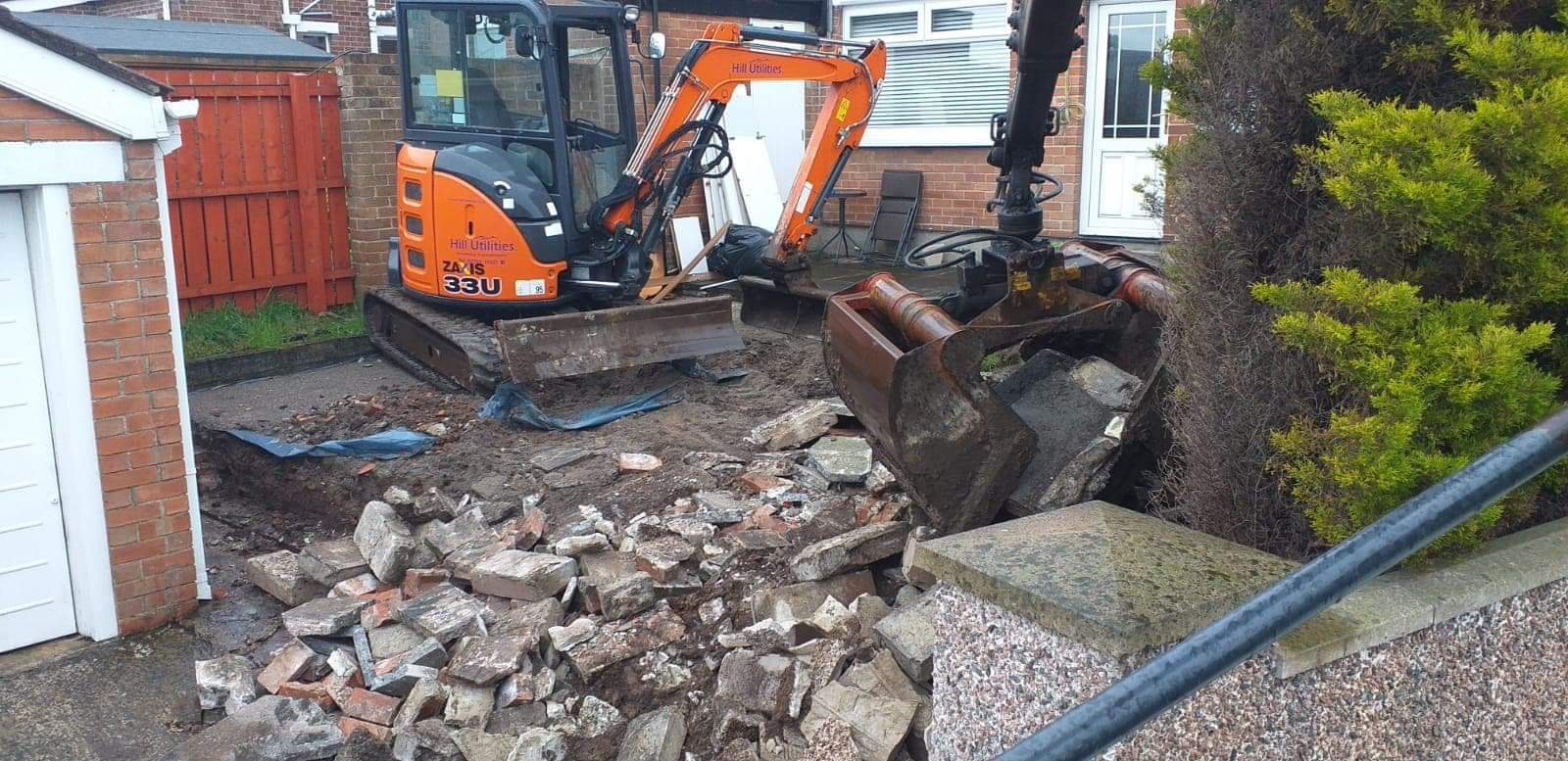 A mini-excavator clearing and breaking out a domestic front garden.