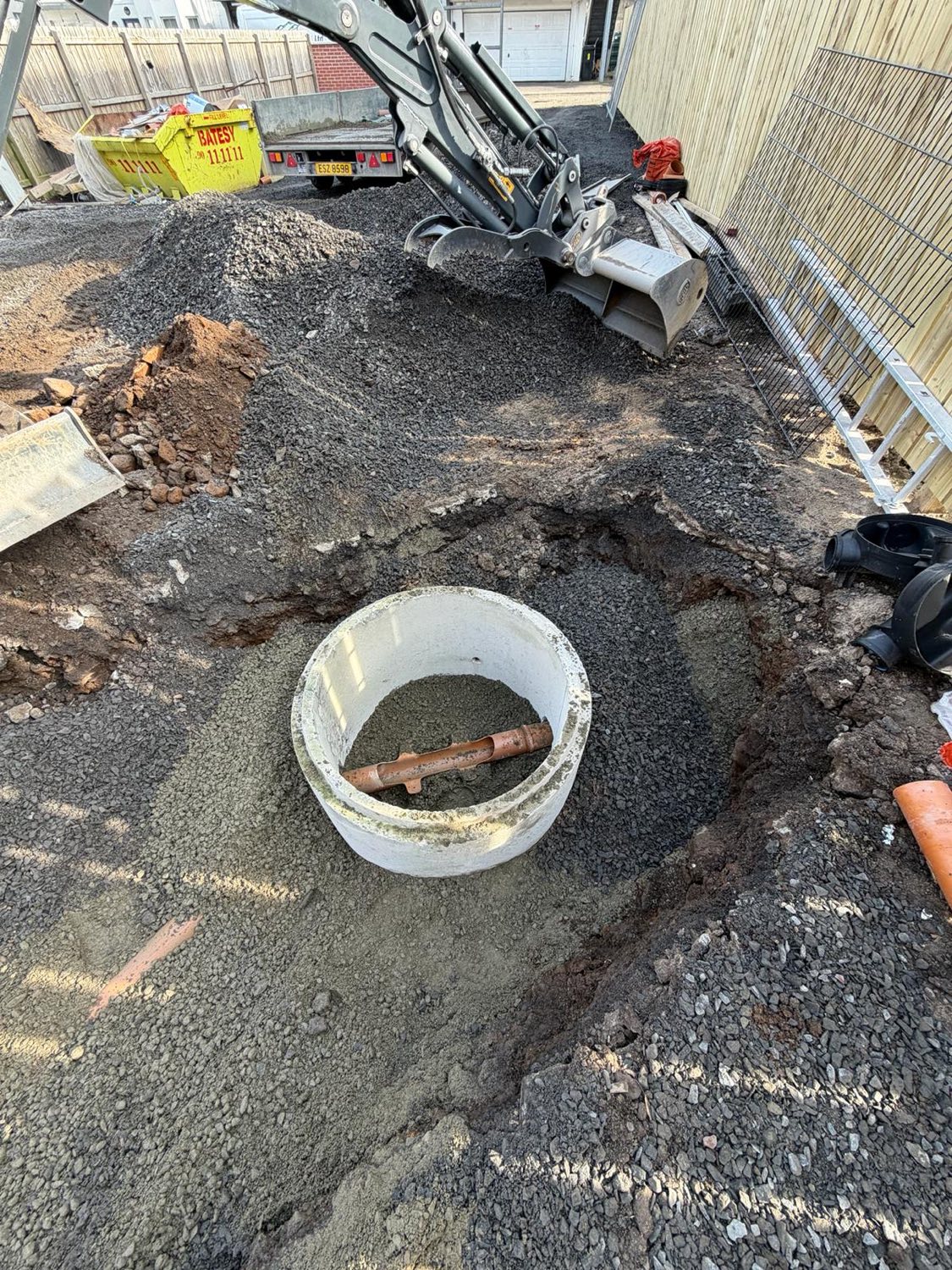 A precast concrete inspection chamber bedded into a stone surround on a new-build site.