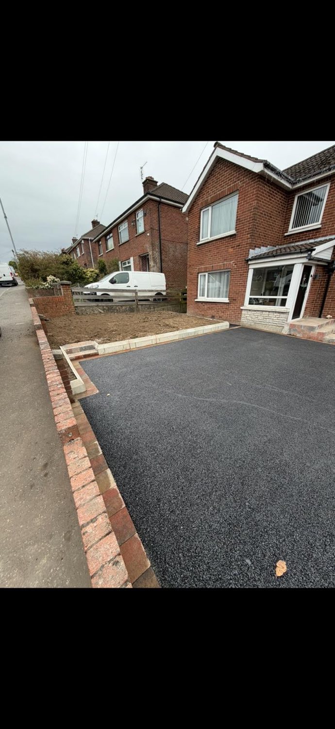A freshly laid tarmac driveway with a new brick boundary wall and pier.